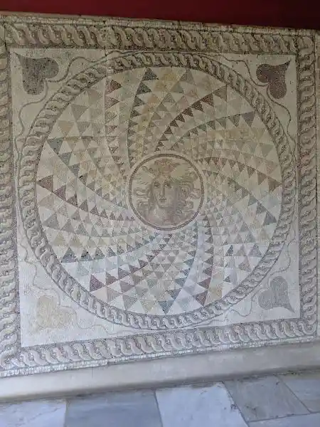 Mosaic floor from Piraeus with a Gorgon medallion and radial patterns.